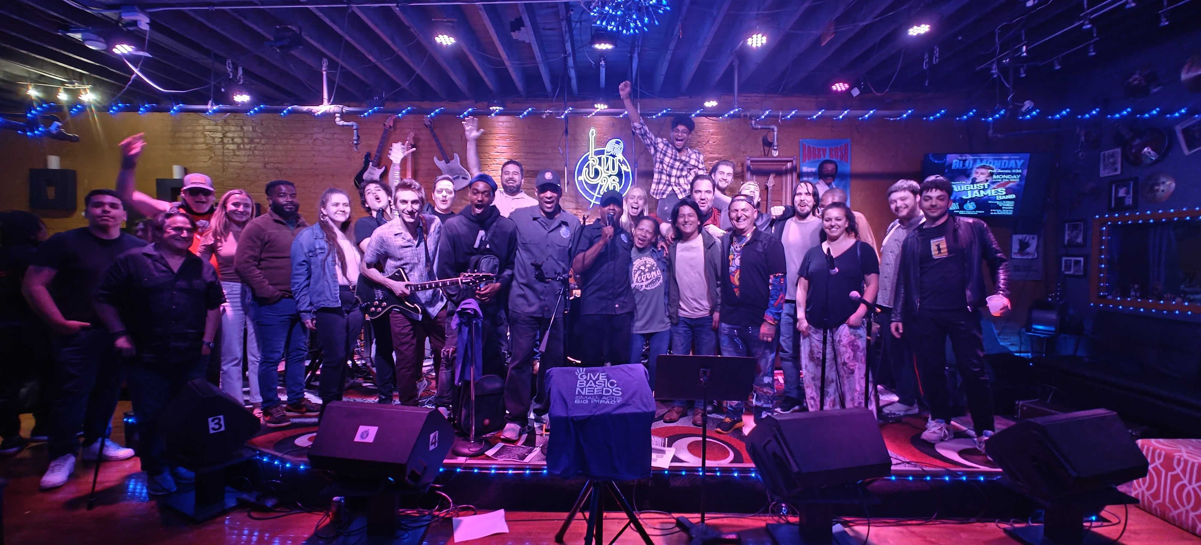 Group photo from the last Blu 22 Blues Jam in Chicago with musicians and attendees on stage