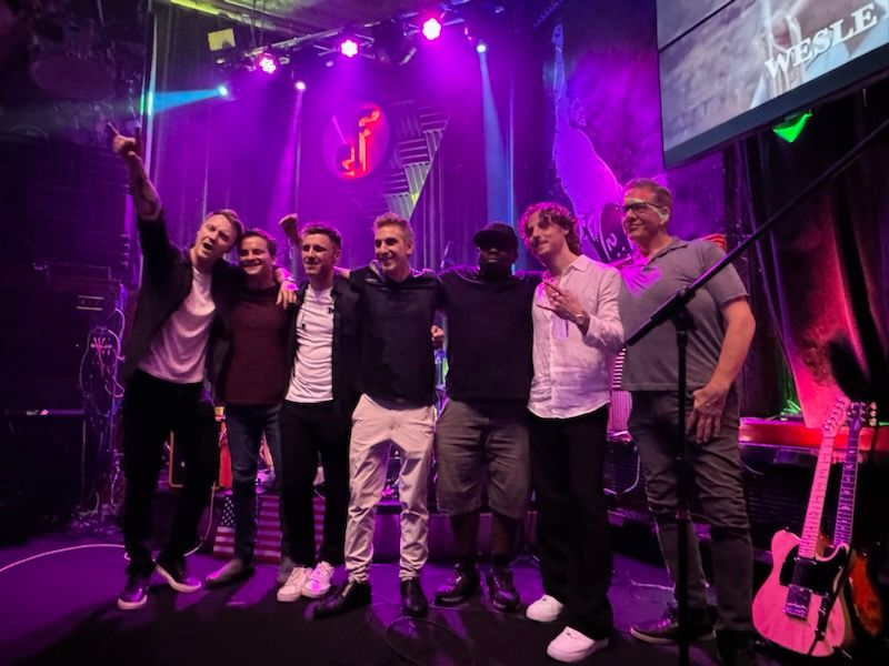 Group photo of musicians on stage at Even Flow with purple lighting