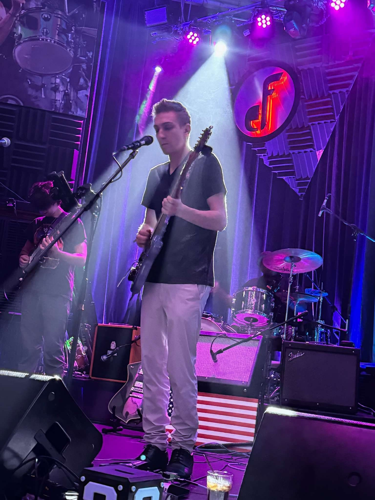 August James performing solo on stage with guitar and microphone at Even Flow